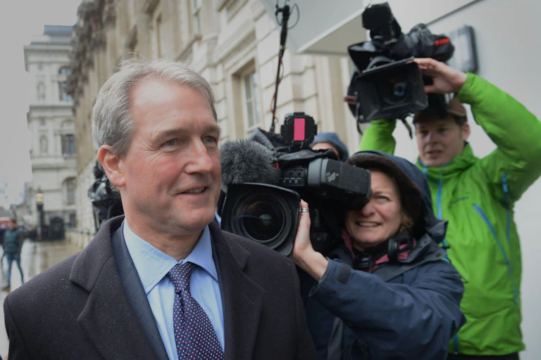 Former COnservative MP, Owen Patterson, surrounded by journalists and TV cameras.