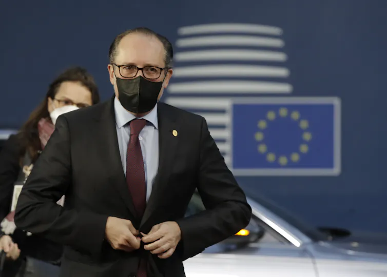 Alexander Schallenberg wears a face mask at an EU event. An EU flag is pictured on the wall behiind him.