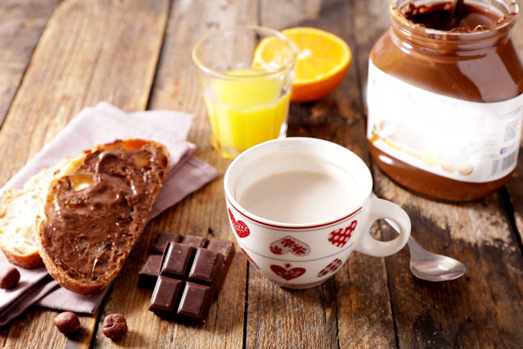 Deux tartines de pâte chocolatée avec fruit et verre de lait constituent un petit-déjeuner continental