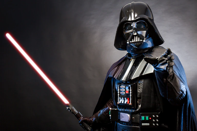 Photo of a Darth Vader costume replica with one arm outstretched and the other holding a lightsaber