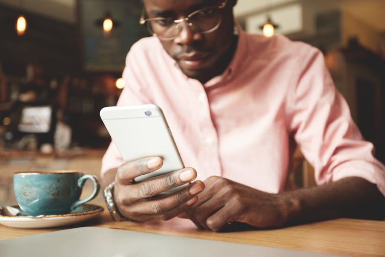 A man using a smartphone in a cafe.