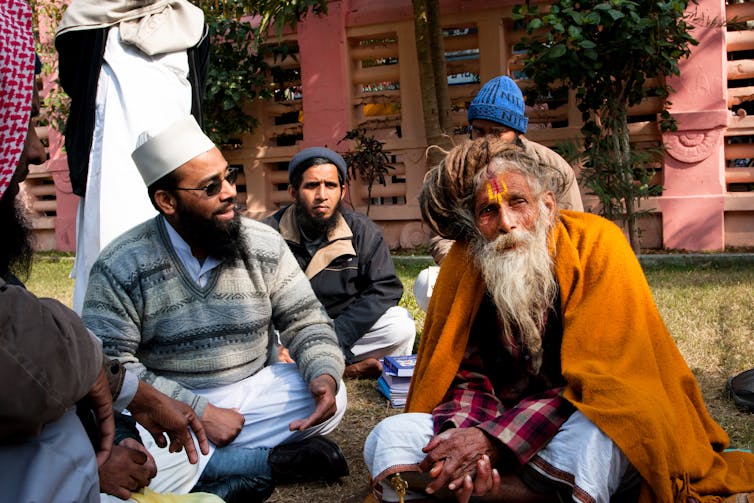 A Muslim group sitting and talking with an elderly Hindu man.