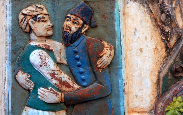 Wall art of Indian Hindu and Muslim hugging each other in religious tolerance and harmony.