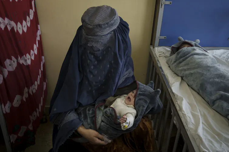 Une femme voilée tient un bébé dans ses bras