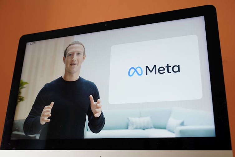 En skärm som visar Mark Zuckerberg och den nya Meta-logotypen