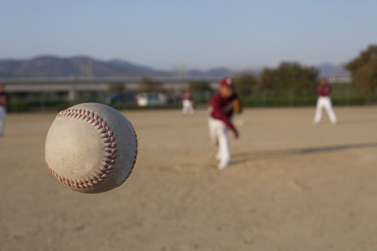 baseball in foreground, pitcher in distance