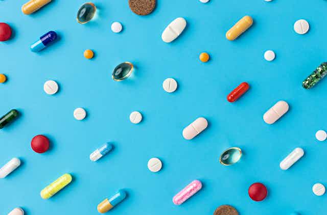 Pills and tablets arranged diagonally on blue background