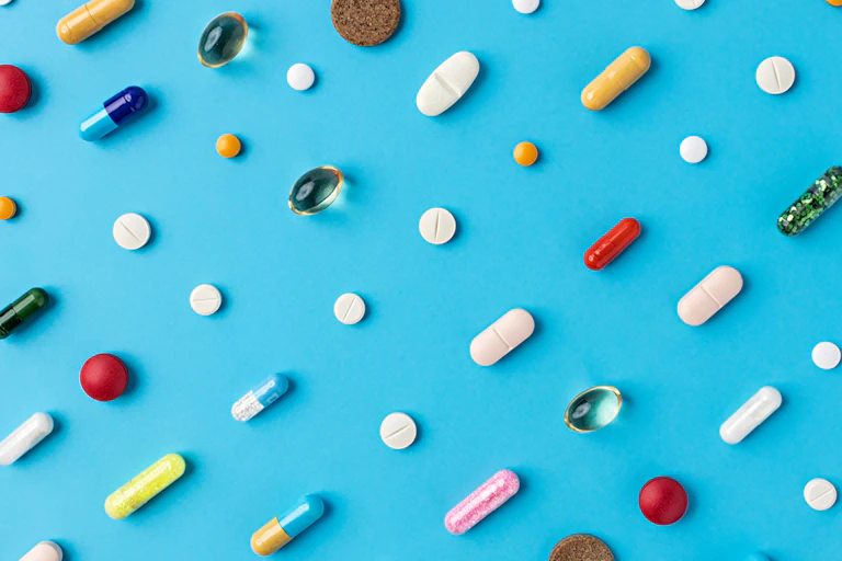 Pills and tablets arranged diagonally on blue background
