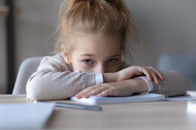 Frustrated unhappy little schoolgirl puts down pencil 