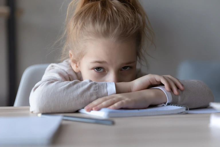 Frustrated unhappy little schoolgirl puts down pencil