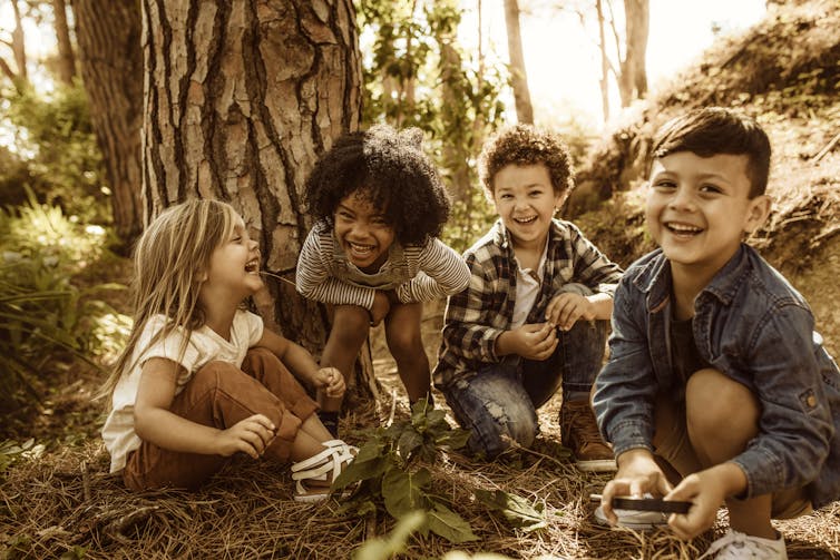 Group of laughing and smiling children together among trees