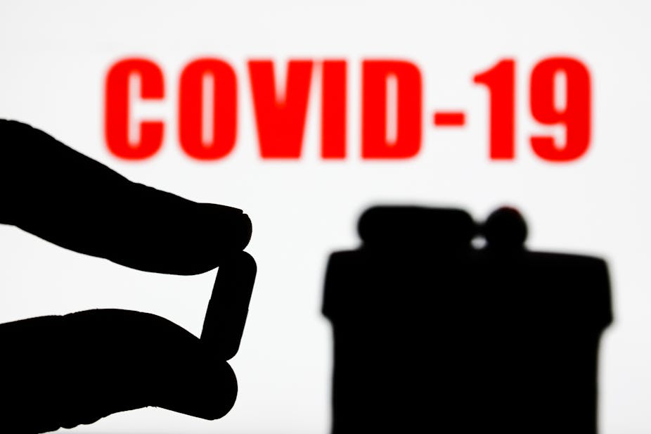 pill is seen with the word 'COVID-19' displayed on a screen