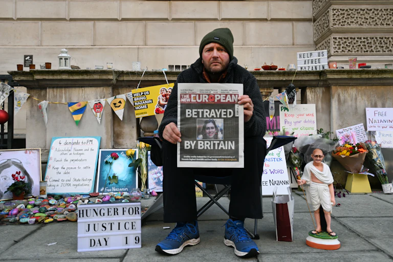 Richard Ratcliffe, on day 19 of his hunger strike, sits outside the foreign office holding up the front cover of a newspaper with a story about his wife Nazanin Zaghari-Ratcliffe who is detained in Iran.