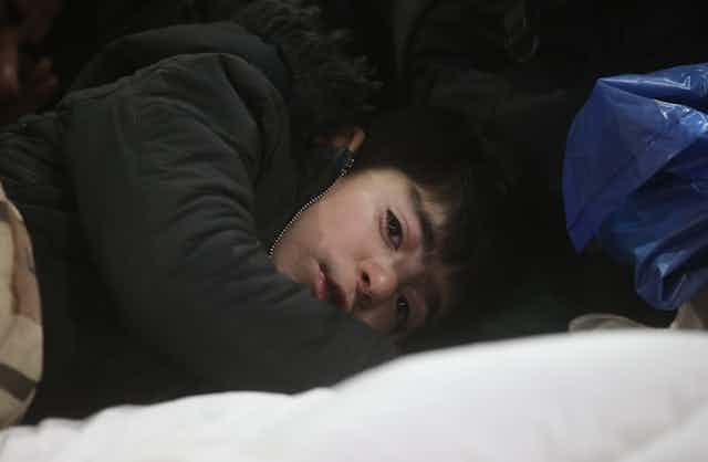 A close-up photo of a young boy wearing a winter coat and lying down to go to sleep