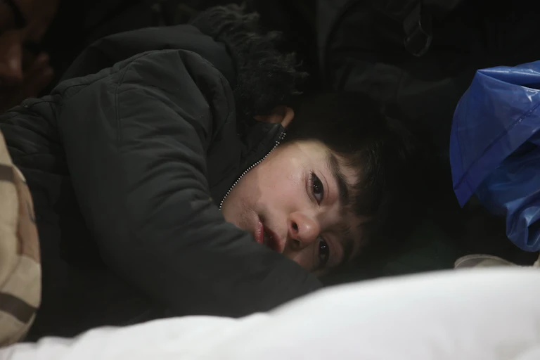 A close-up photo of a young boy wearing a winter coat and lying down to go to sleep