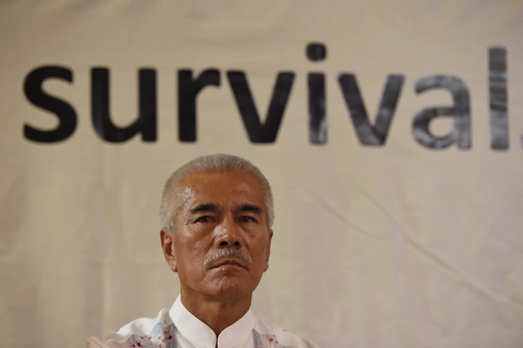 man looks at camera in front of the word