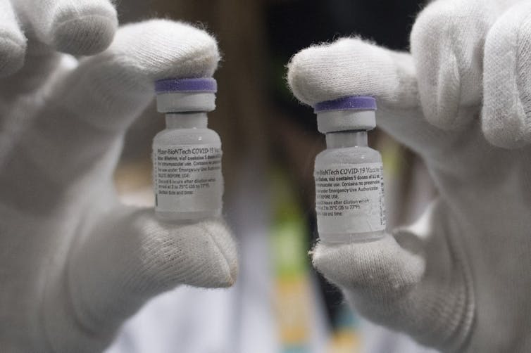 Un technicien tient deux fioles de vaccin Pfizer contre le Covid