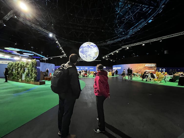 A man and a woman, from behind, contemplate the space set up for COP26