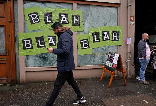 A man walks by a storefront in Glasgow, Scotland, during the UN climate change summit. On the store's window are the words: Blah, blah, blah.