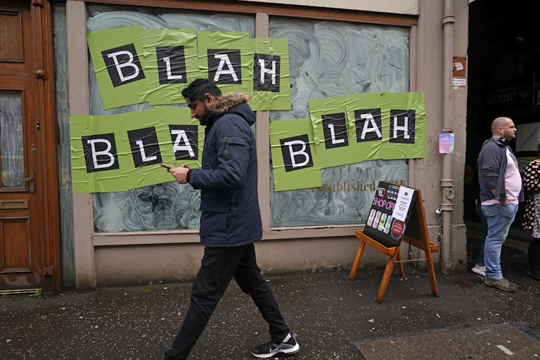 A man walks by a storefront in Glasgow, Scotland, during the UN climate change summit. On the store's window are the words: Blah, blah, blah.