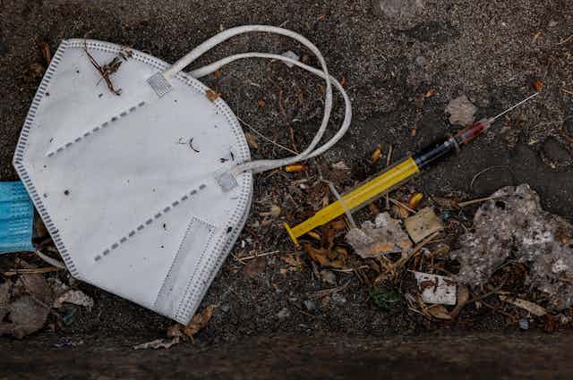 A discarded face mask and a syringe.