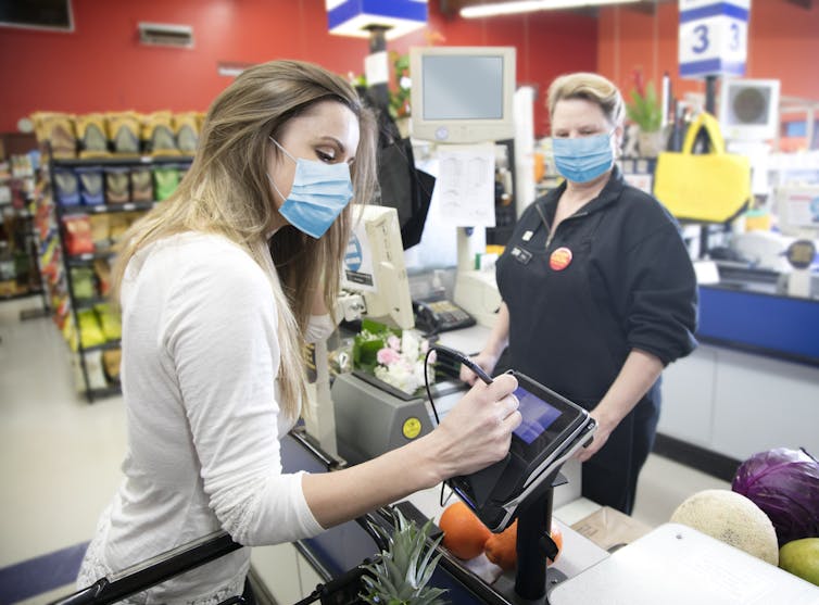 A cashier serving a customer in a supermarket checkout lane.