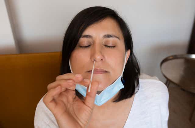 Women inserting nasal swab up own nose
