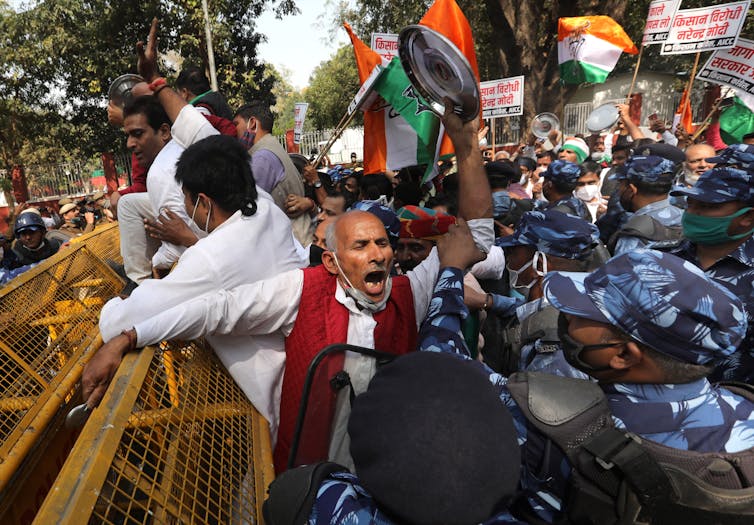 Police and protesters against a barricade on a packed street.
