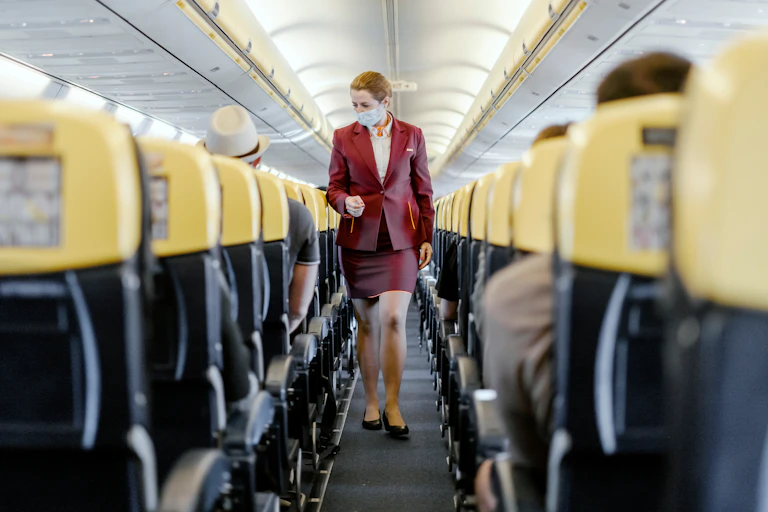 A flight attendant wearing a face mask walks down the aisle of a nearly empty Ryanair flight