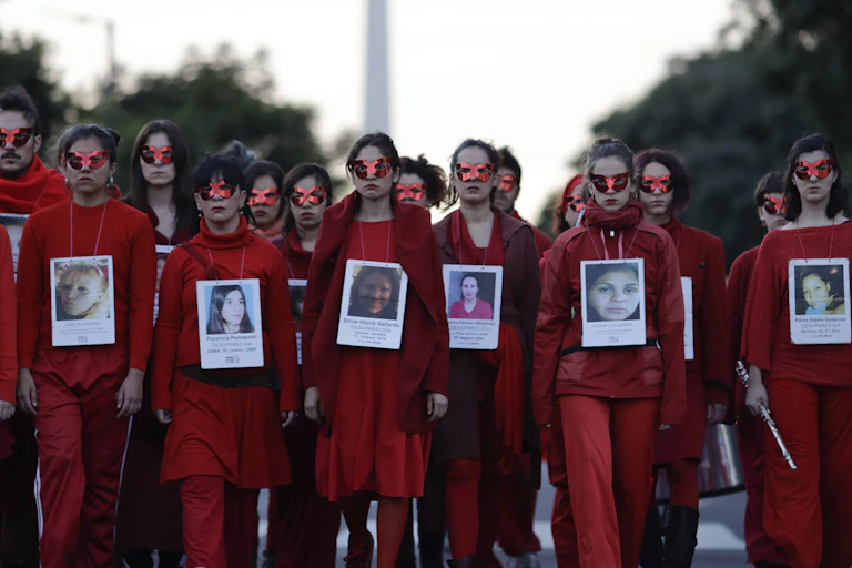 People wear read with photos of victims on their chests.