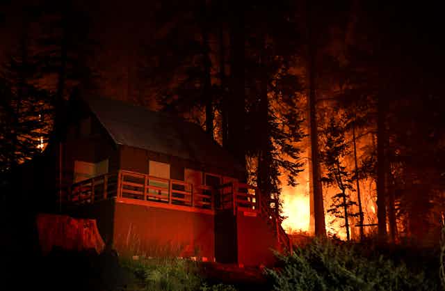 Mountain cabin with trees and flames in the background