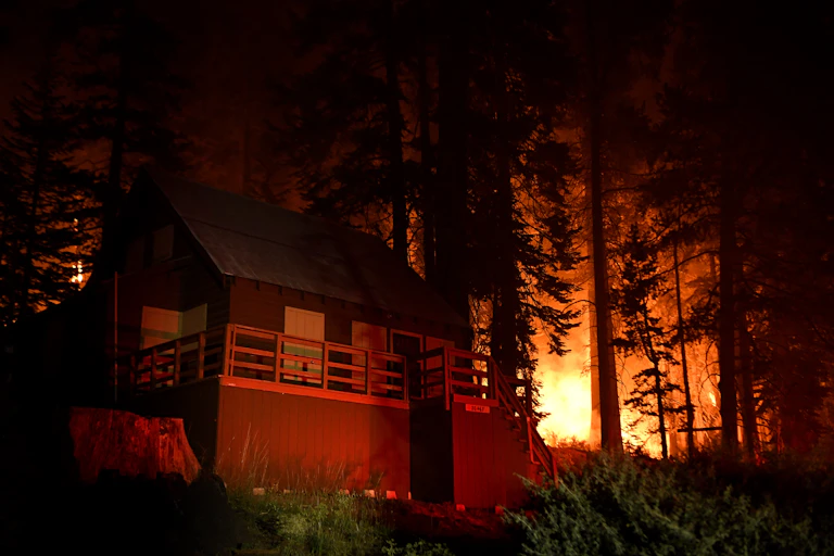 Mountain cabin with trees and flames in the background