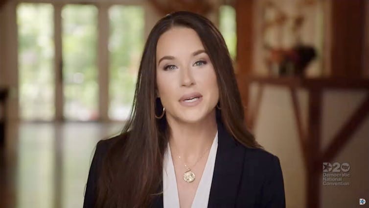 A dark-haired young woman in a black jacket and white blouse.