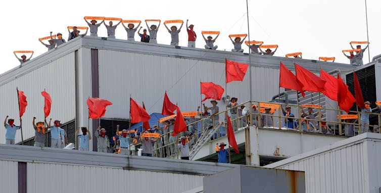 Workers are seen on top of a manufacturing plant.