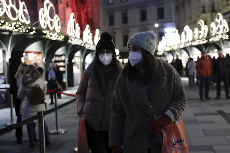 TO WOMEN IN MASKS AND HATS AT CHRISTMAS MARKET