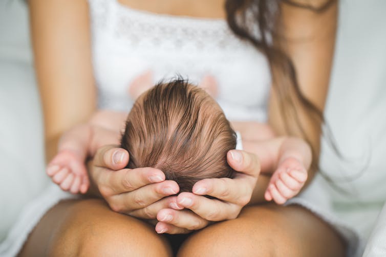 Mum holding a new baby in her lap.