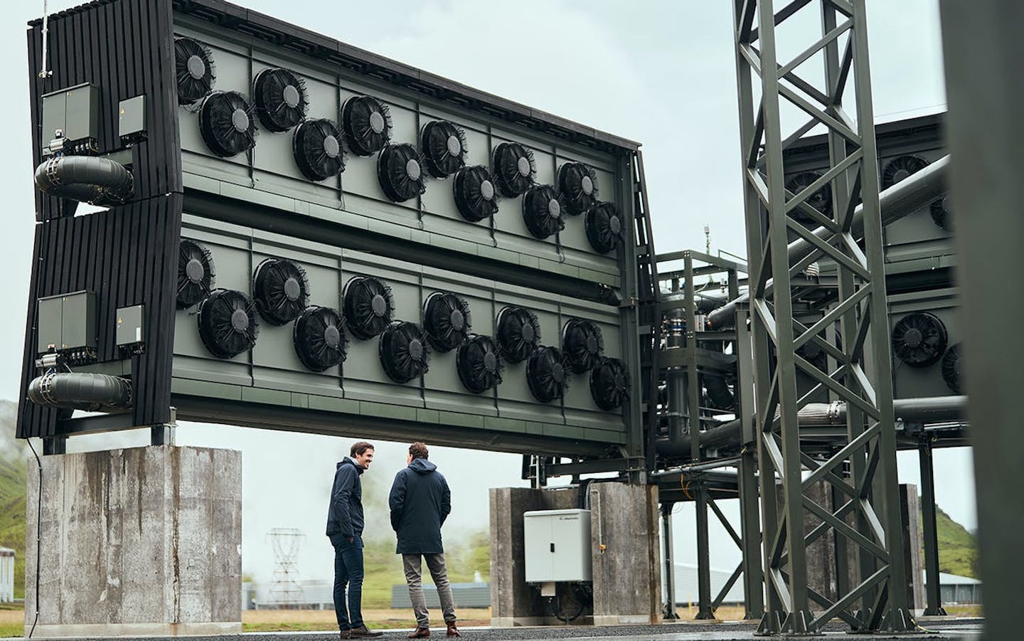 两名男子站在一个装有风扇的大型建筑下面