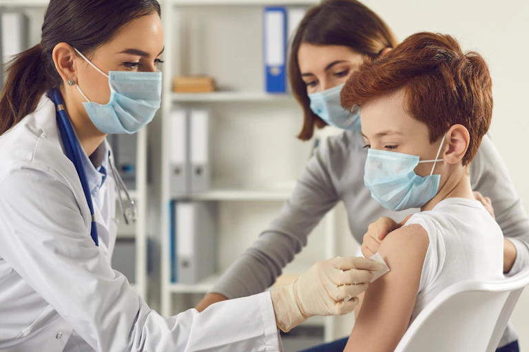 A young boy being vaccinated by a nurse while his mum watches