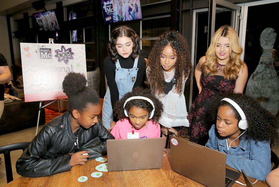 A group of girls surround a laptop.