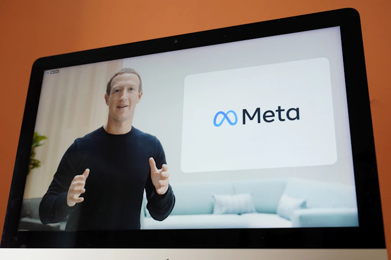 A video screen showing a man looking at the camera while gesturing with both hands with a corporate logo beside him
