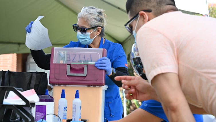 A nurse gets ready to give people the Pfizer COVID-19 vaccine.