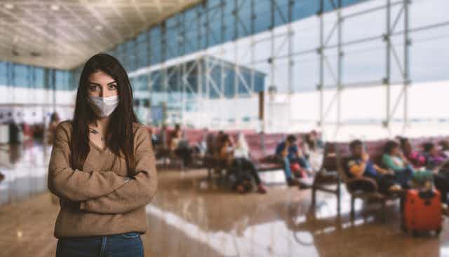 Jeune femme portant un masque pour se protéger à l'intérieur de l'aéroport 