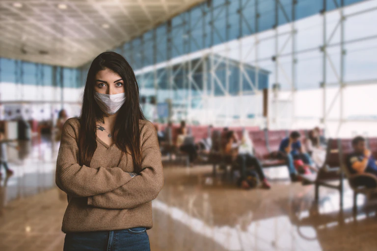 Jeune femme portant un masque pour se protéger à l'intérieur de l'aéroport