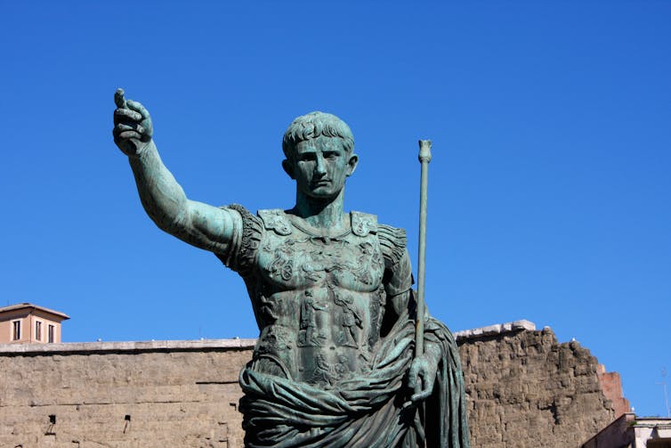 A statue of emperor Augustus with a blue sky background.
