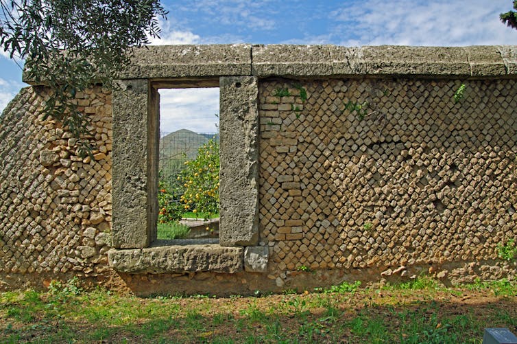 An image of a stone wall with grass in the foreground and a blue sky in the background