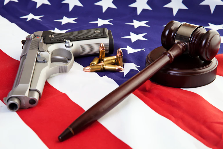 A gavel, gun and bullets are strewn over a US flag.