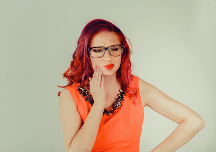 A woman clasps her jaw.