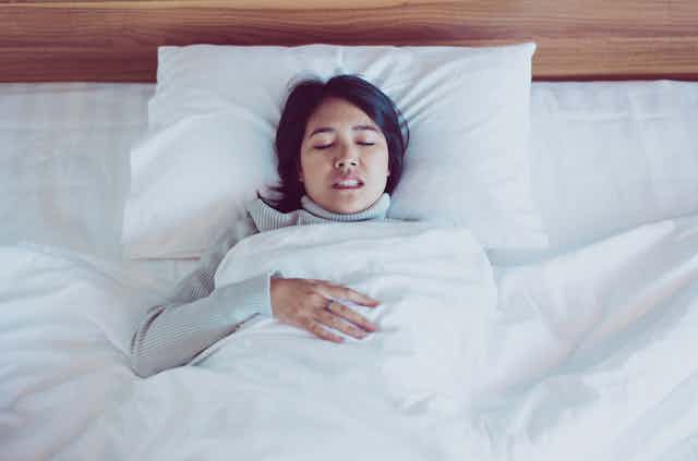 A woman grinds her teeth in bed.