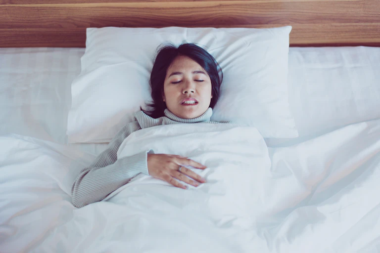 A woman grinds her teeth in bed.