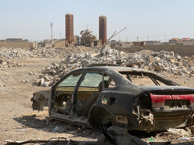 A burned-out car in front of the rubble of bombed-out buildings in Hawija, Iraq.